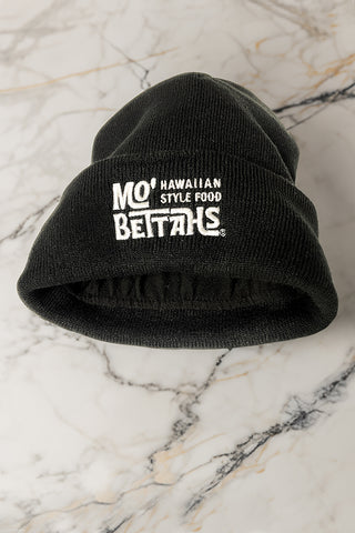 Black cuffed beanie, showing fleece lining, laying on marble countertop. Also shows an embroidered Mo' Bettahs Hawaiian Style Food logo.