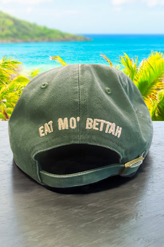 Back view of Mo' Bettahs hat, on counter with ocean view, reading "Eat Mo' Bettah".