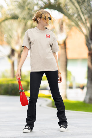 Front view of young woman, walking on sidewalk, holding matching red purse, wearing Live Mo' Bettah beige t-shirt.