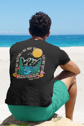 Man looking out at ocean, wearing black T-Shirt with Shaka mountain tropical graphic on back of t-shirt.